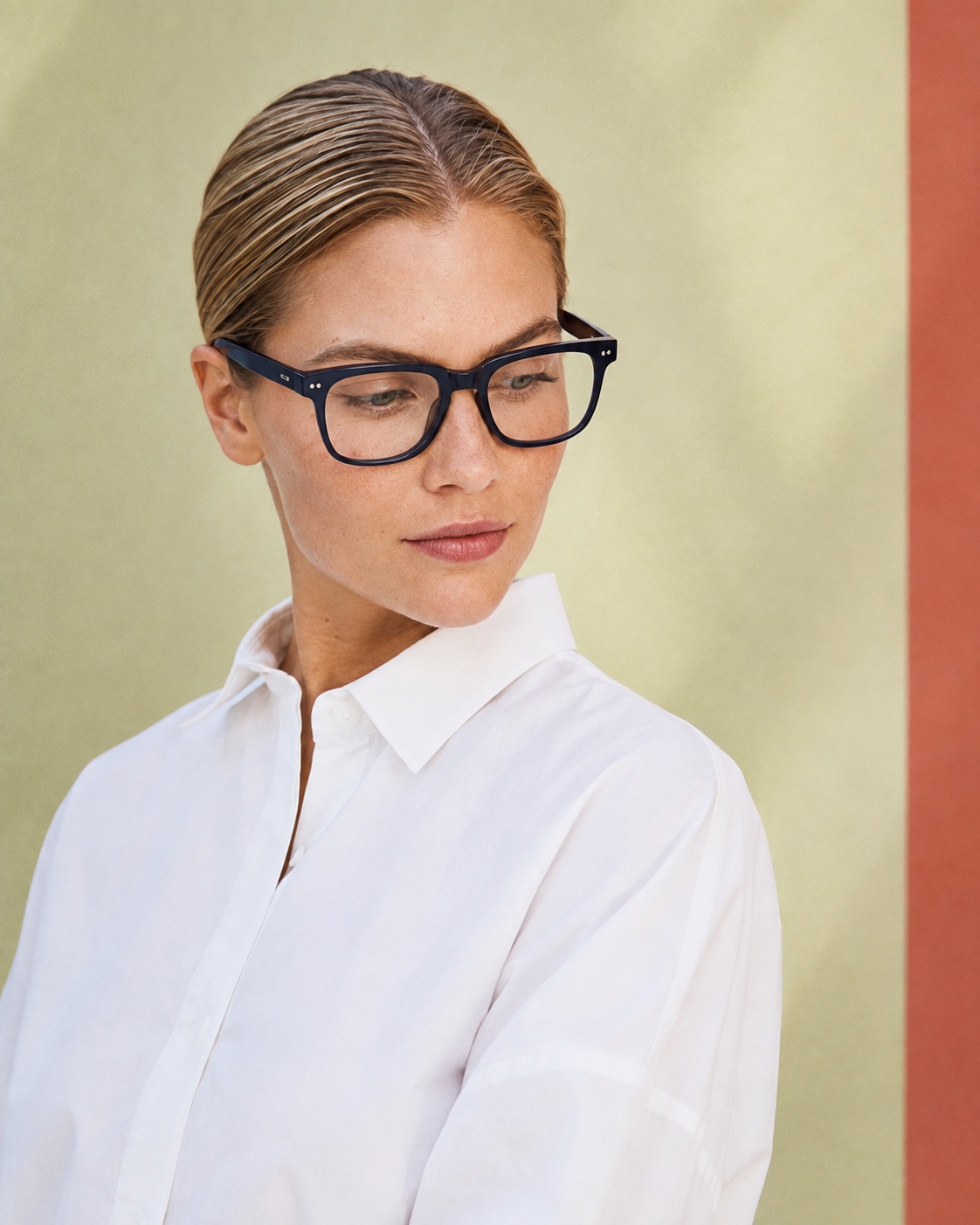 A blonde Visionne model wearing dark acetate eyeglasses